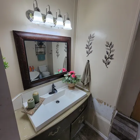 Vanity with an integrated rectangular sink, dark finish cabinetry, and a framed wall mirror