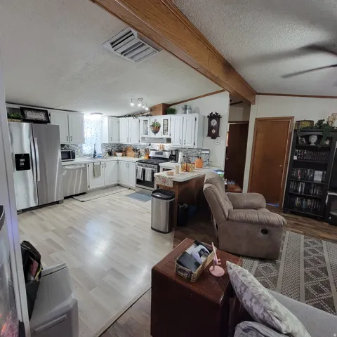 Kitchen featuring white cabinetry, stainless steel appliances, a tiled backsplash, and wood-finish flooring