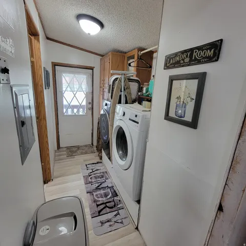 Laundry area featuring wood-finish flooring, built-in cabinetry, and a white exterior door with decorative lites