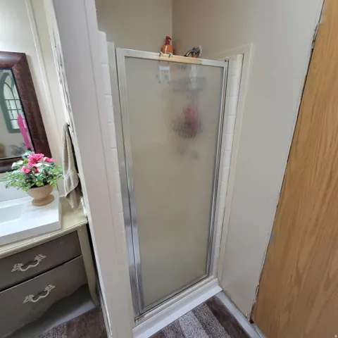 Shower enclosure with frosted glass door, chrome frame, and tile surround
