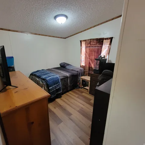 Recessed ceiling light fixture, wood-finish flooring, white walls, and wood-trim crown molding