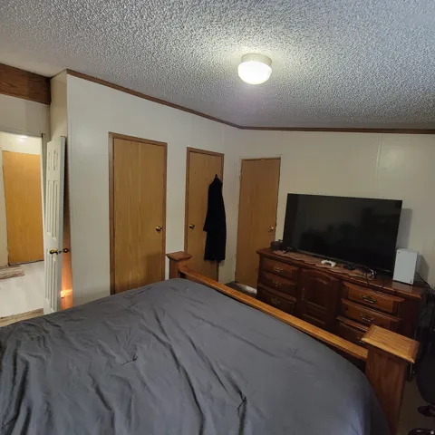 Recessed lighting with a textured ceiling, multiple wood-panel doors, and wood-finish trim