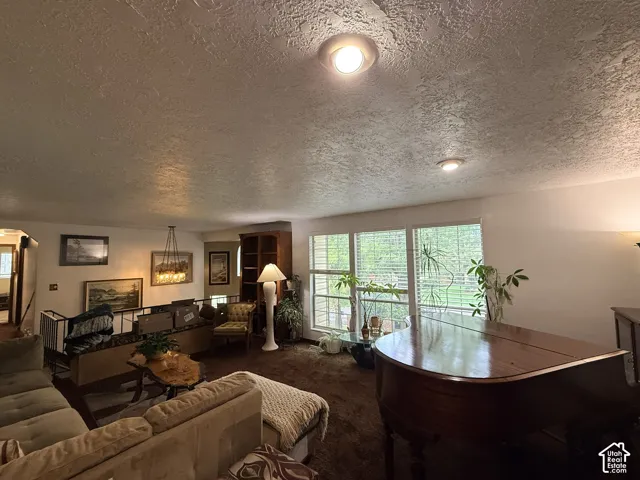 Recessed ceiling lighting, textured ceiling finish, chandelier lighting fixture, built-in shelving, and multiple windows