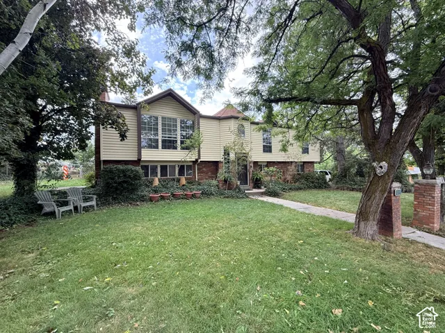 Split-level residence featuring a brick and siding exterior, large bay windows, and a mature treed lot