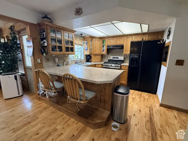 Kitchen with wood-finish flooring, wood cabinetry, stone countertops, and stainless steel appliances