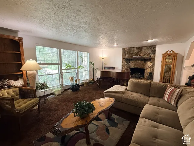 Living area featuring a stone fireplace, recessed lighting, expansive windows with blinds, and built-in shelving