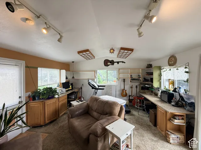 Spacious room with a vaulted ceiling, track lighting, dual windows, and built-in cabinetry with countertops