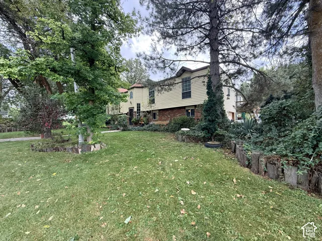 Expansive lawn with mature trees, a multi-level residence featuring siding and brick construction, and a distinct turret architectural element
