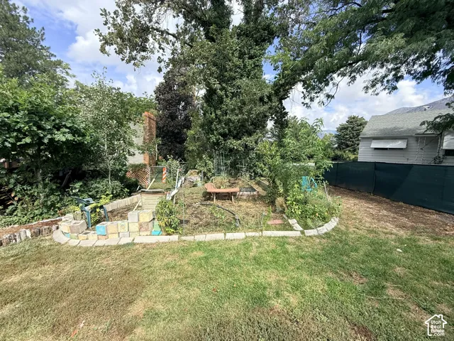 Expansive backyard featuring a tiered garden area, mature trees, and a privacy fence