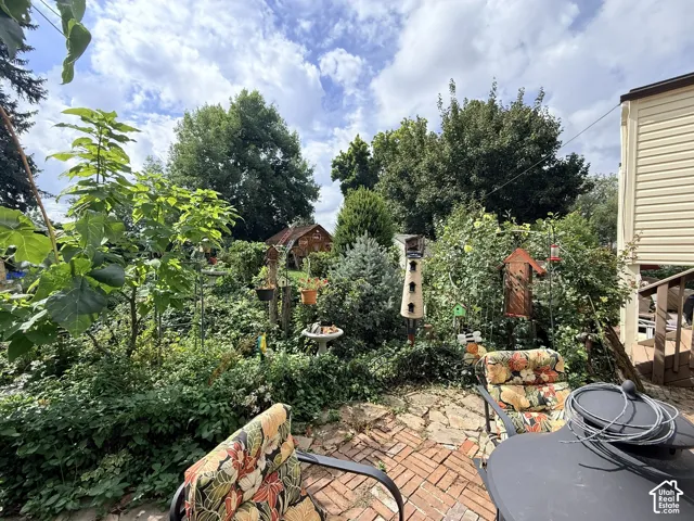 Brick paver patio with a lush, mature garden, surrounded by diverse plantings, and featuring a wood-sided structure