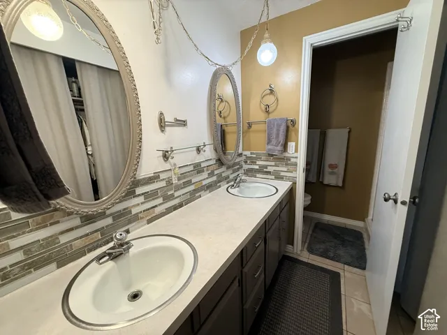 Dual vanity with integrated sinks, mosaic tile backsplash, and individual oval mirrors