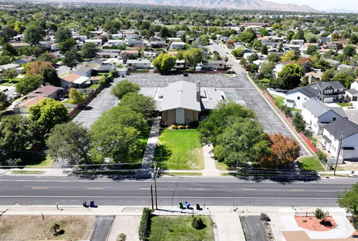 Expansive asphalt parking lot, mature trees, and a manicured lawn