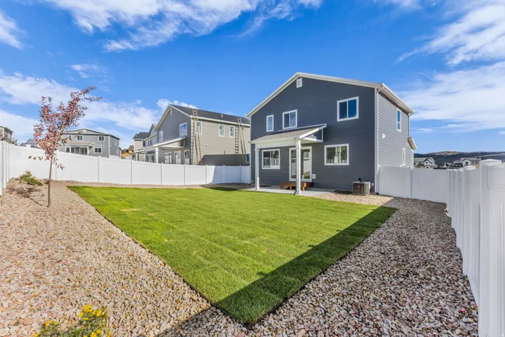 Expansive backyard featuring a manicured lawn, gravel landscaping, and a full privacy fence