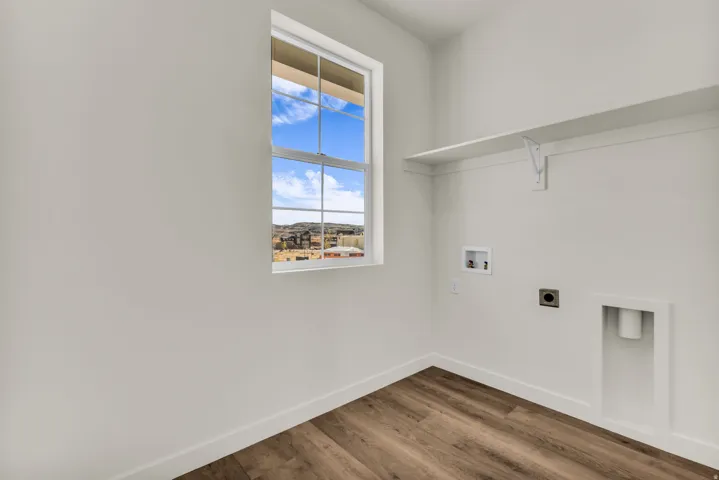 Functional utility space featuring a single window, overhead shelving, and wood-finish flooring