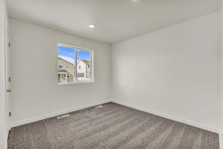 Recessed ceiling lighting, neutral-toned walls, and grey carpet flooring