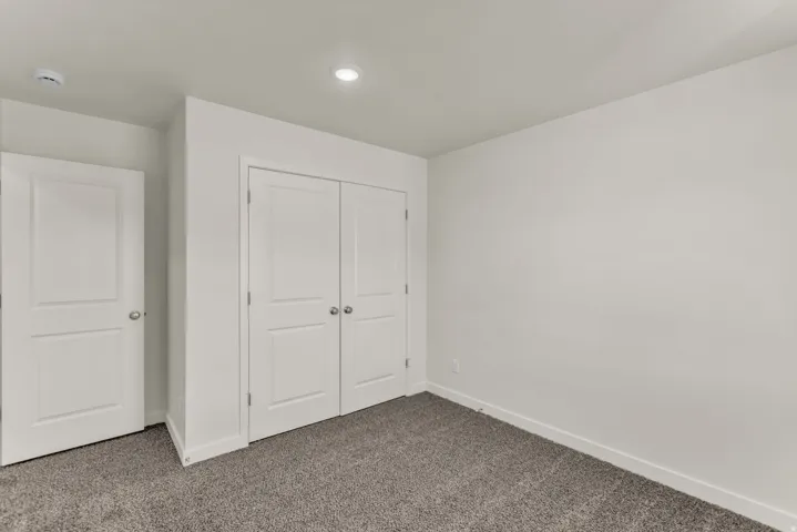 Recessed ceiling lighting, gray carpeting, white walls, and white paneled doors