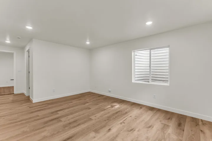 Wood-finish flooring, recessed ceiling lighting, and a white framed window