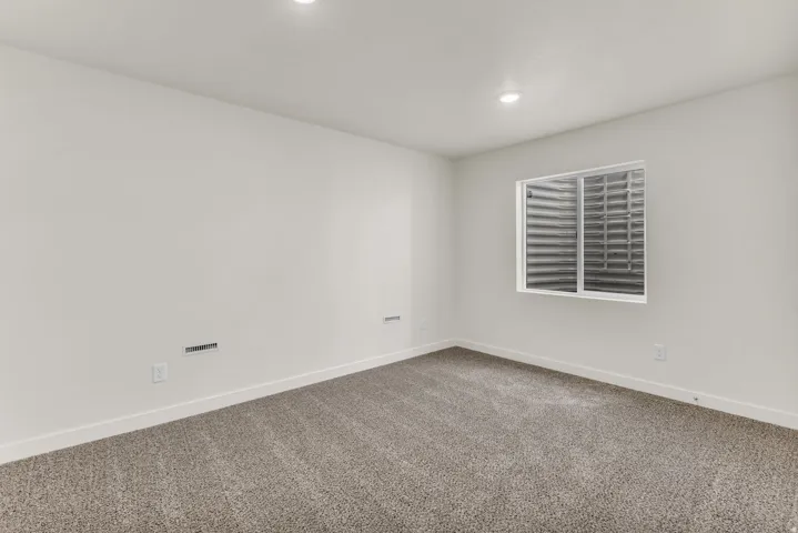 Recessed ceiling lighting, a window, and gray carpet