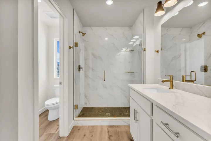 Wood-finish flooring with a white vanity featuring a single basin and gold-tone fixtures