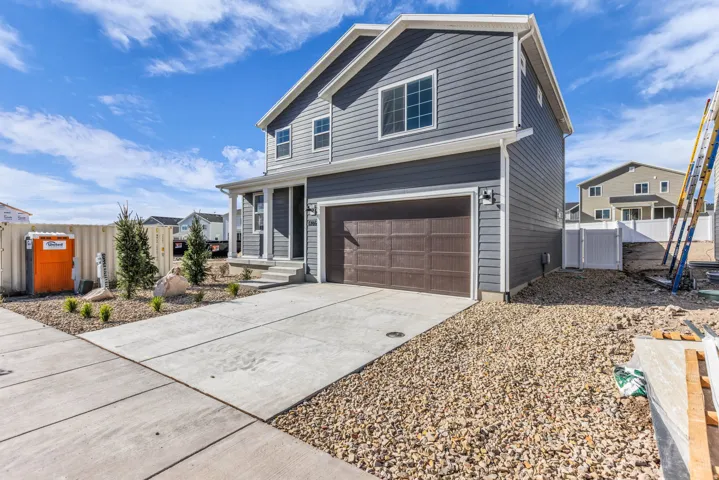 Two-story exterior with dark gray siding, an attached two-car garage, covered porch, and concrete driveway