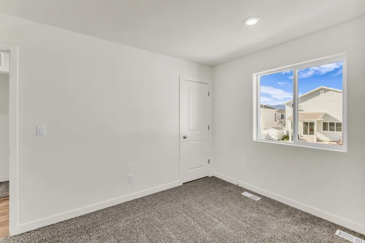 Recessed ceiling lighting, white walls, white trim, carpeted flooring, and a multi-pane window