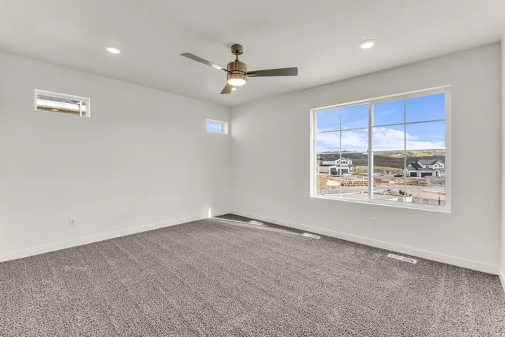 Spacious room featuring a large window, recessed lighting, ceiling fan, and grey carpet