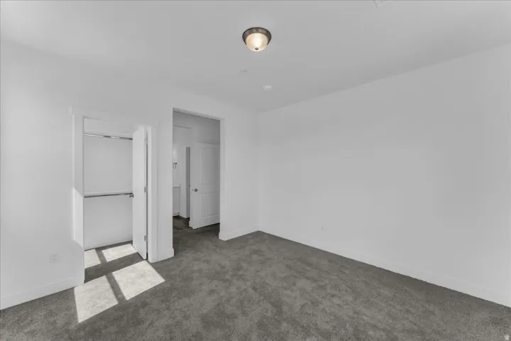 Plush carpet flooring, neutral wall tones, semi-flush mount ceiling light, and built-in closet shelving