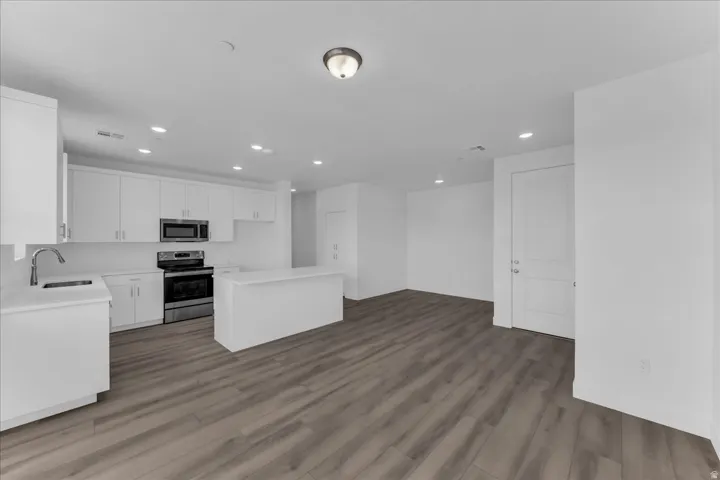 Kitchen featuring white shaker cabinetry, stainless steel appliances, white countertops, and an island