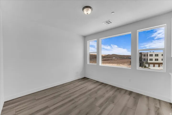 Wood-finish flooring, multiple windows, a ceiling-mounted light fixture, and white painted walls