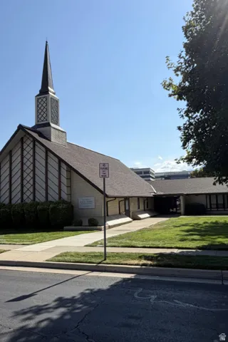 Building with a dark shingle roof, a steeple, and a light-colored brick exterior