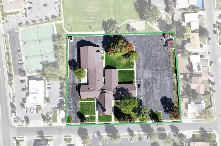 Expansive parcel featuring multiple buildings, substantial paved parking areas, and mature landscaping