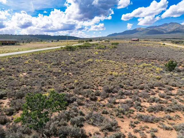 Expansive lot with natural desert vegetation, a paved road, and distant mountain scenery