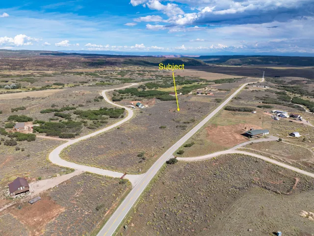 Expansive undeveloped land featuring a paved road frontage and distant mountain ranges