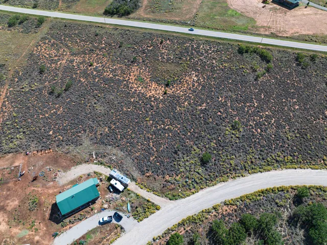 Expansive land parcel featuring natural desert vegetation, a long private drive, and a detached structure with a green metal roof