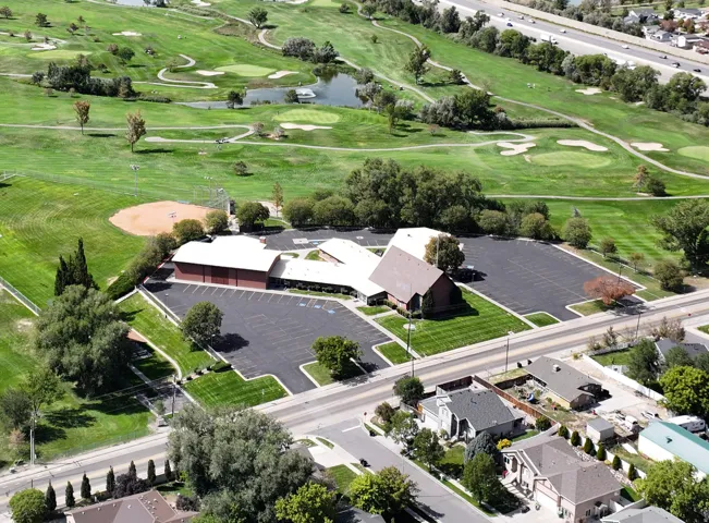 Expansive paved parking areas, surrounding green spaces, and adjacent golf course with water features