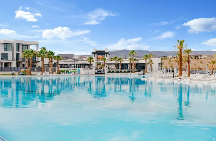 Expansive blue water feature surrounded by modern architecture, complemented by palm trees and mountains in the background