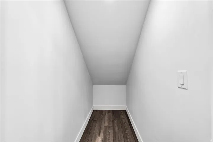 Under-stair storage area with wood-finish flooring and white baseboards