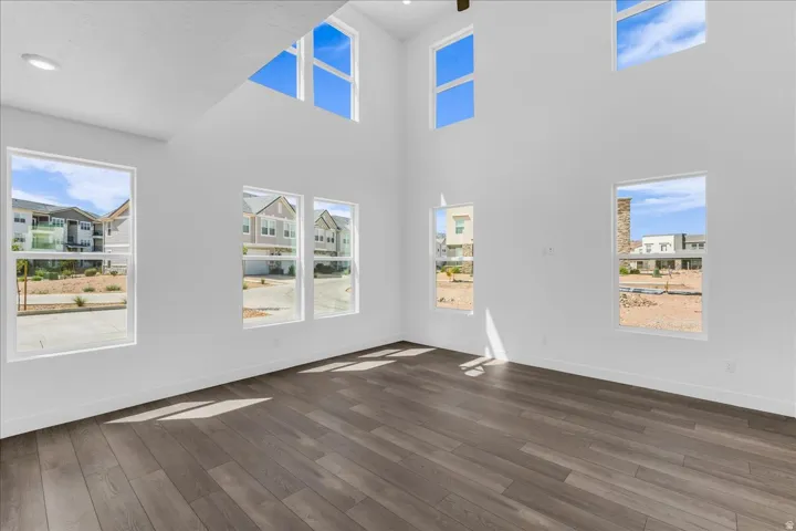 Vaulted ceilings with high windows, wood-finish flooring, recessed lighting, and bright white walls