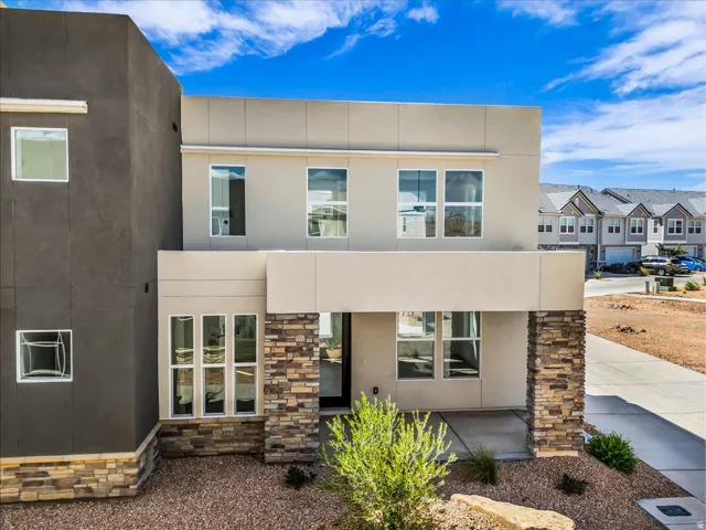 Modern exterior with a flat roofline, stucco finish, stone veneer accents, and an integrated entryway