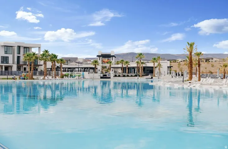 Expansive lagoon with a white sand edge, surrounded by palm trees and modern architectural structures