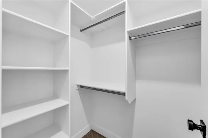 Walk-in closet with integrated white shelving and multiple clothing rods