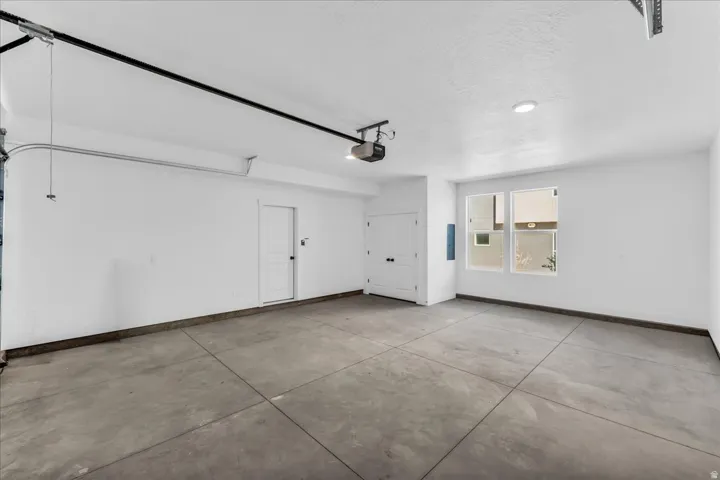 Concrete flooring, recessed lighting, white walls, built-in storage, and two windows