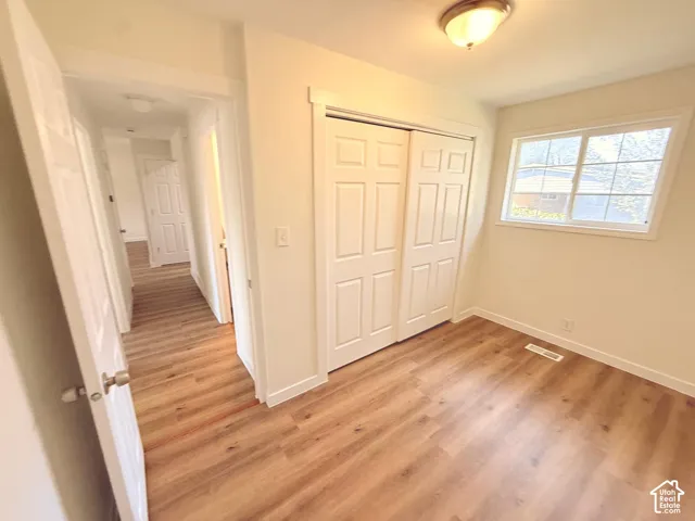 Wood-finish flooring, white trim, and a window with grid detailing