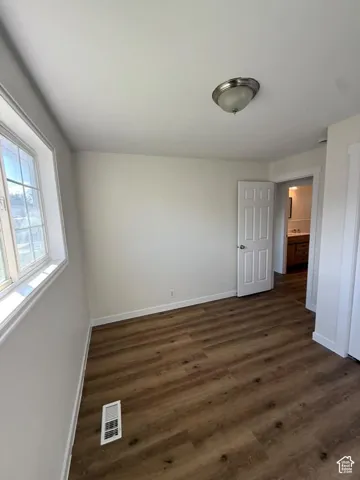 White interior walls, wood-finish flooring, white trim, flush mount ceiling light, and a white paneled door