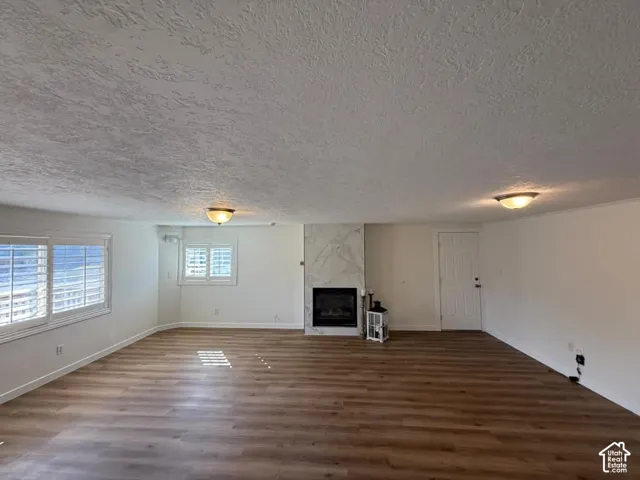 Wood-finish flooring throughout, multiple windows with white plantation shutters, fireplace with a marble-finish surround, and ceiling-mounted light fixtures