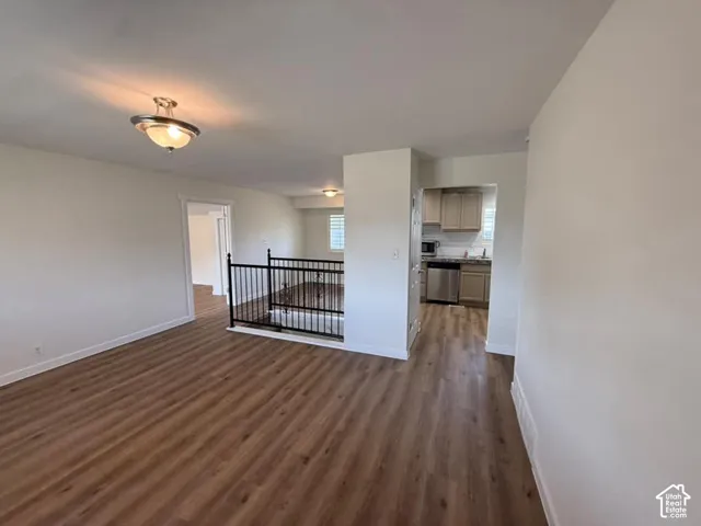 Wood-finish flooring, recessed lighting, and a kitchen featuring light cabinetry, stainless steel appliances, and a tiled backsplash
