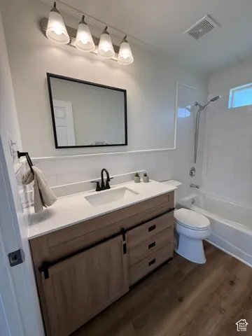 Modern vanity with a light wood-finish, white countertop, and dark-finish hardware