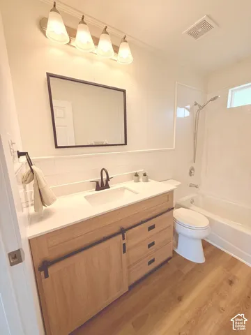 Bathroom featuring a wood-finish vanity with a sliding barn door accent, white countertop, and integrated sink