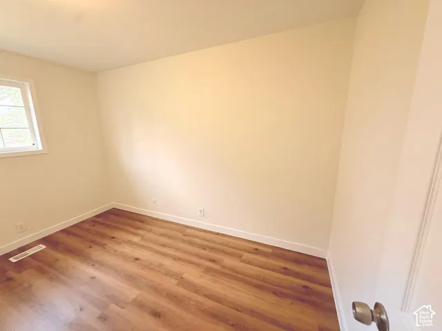 Recessed ceiling lighting, wood-finish flooring, white trim, and a window with white casing