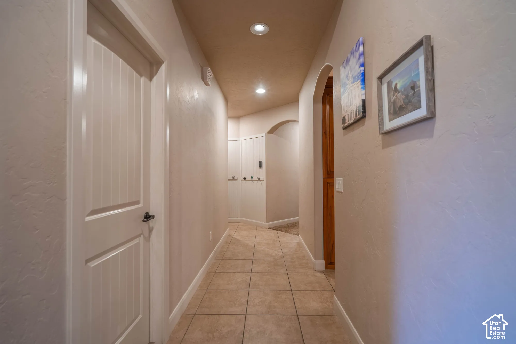 Hallway featuring tile flooring, recessed lighting, arched doorways, and textured wall finishes